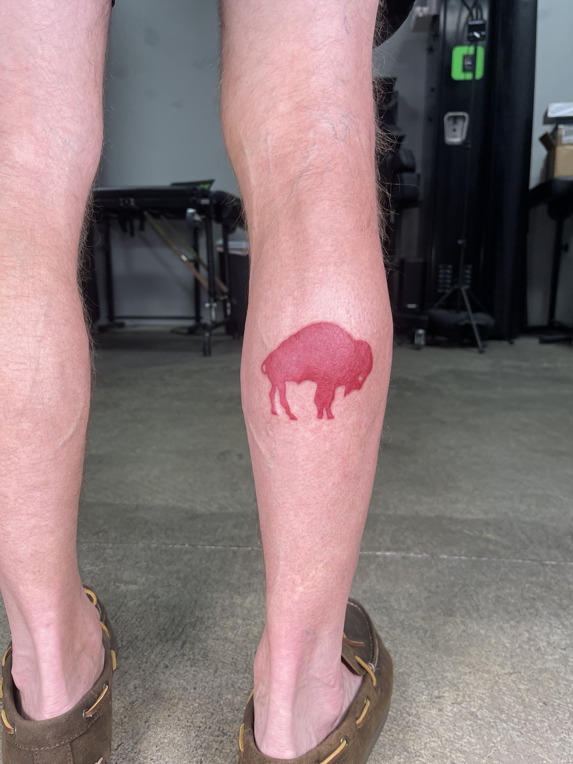 Small red animal silhouette leg tattoo