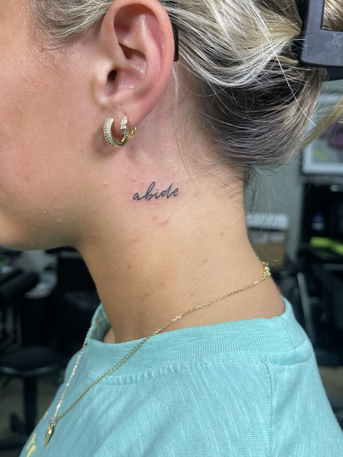 Small script behind ear tattoo